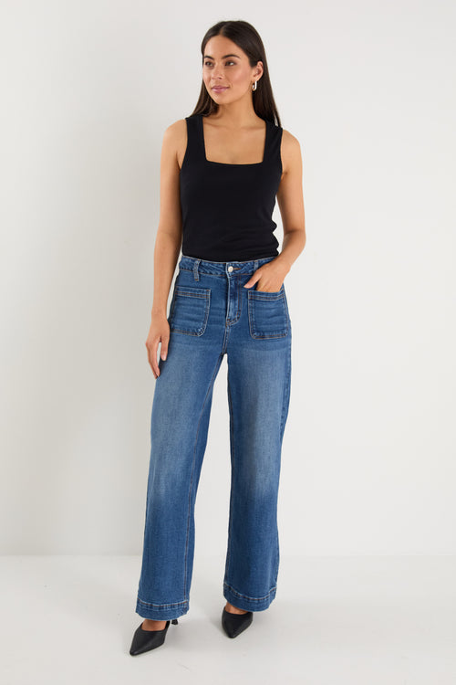 model wears  dark blue wide leg jean with a black tank top