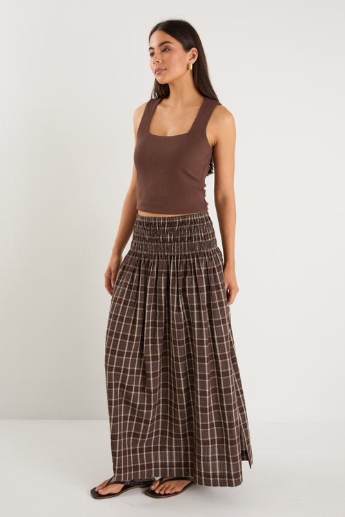 model wears a brown and beige check maxi skirt with a brown tank top