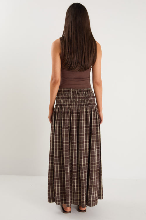 model wears a brown and beige check maxi skirt with a brown tank top
