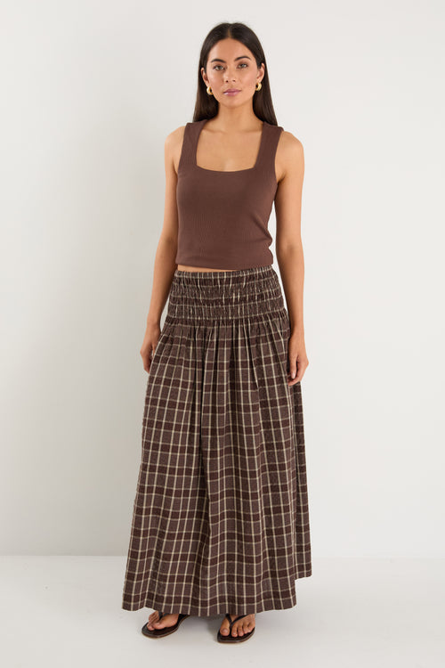 model wears a brown and beige check maxi skirt with a brown tank top