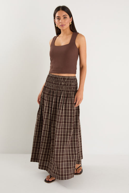 model wears a brown and beige check maxi skirt with a brown tank top