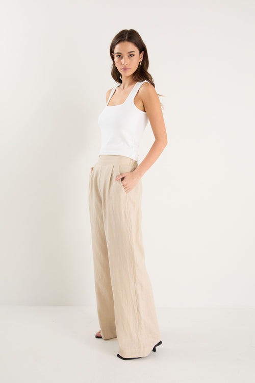 Woman wearing a white top and beige pants on a white background