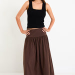 Model wearing a chocolate brown tiered maxi skirt with a flat waistband and shirred back