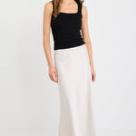 Woman wearing a pearl satin bias-cut maxi skirt with an elastic waistband, styled with a black tank top.