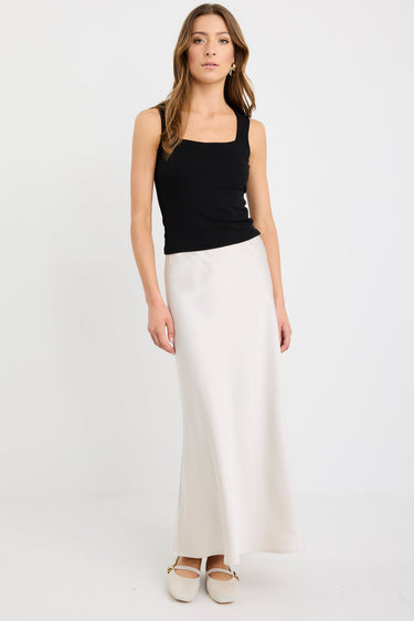Woman wearing a pearl satin bias-cut maxi skirt with an elastic waistband, styled with a black tank top.