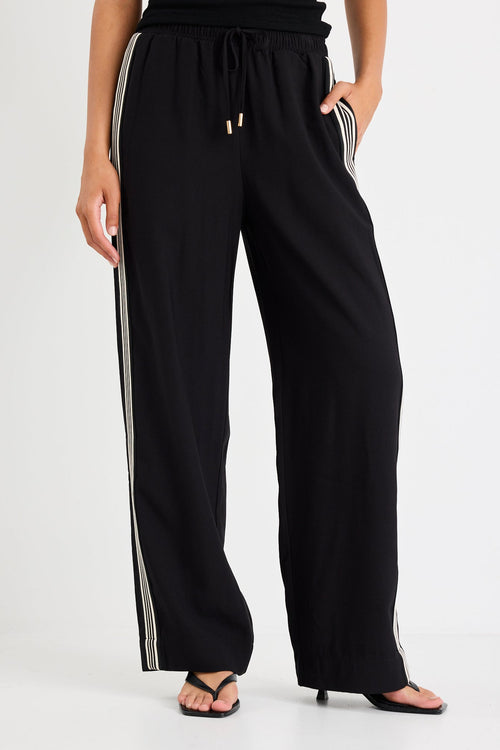 Woman wearing black pants with a side stripe and a black tank top