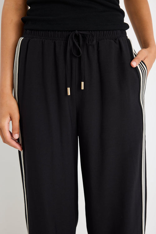 Woman wearing black pants with a side stripe and a black tank top