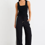 Woman wearing black pants with a side stripe and a black tank top