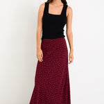Model wearing a burgundy polka dot satin midi skirt with a bias-cut silhouette and a soft drape