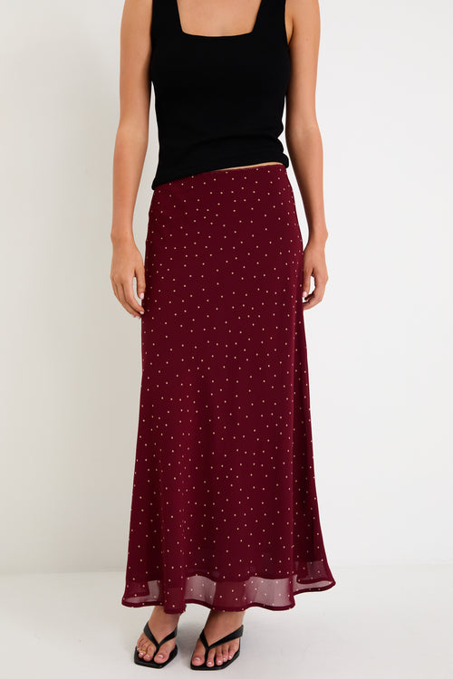 Model wearing a burgundy polka dot satin midi skirt with a bias-cut silhouette and a soft drape