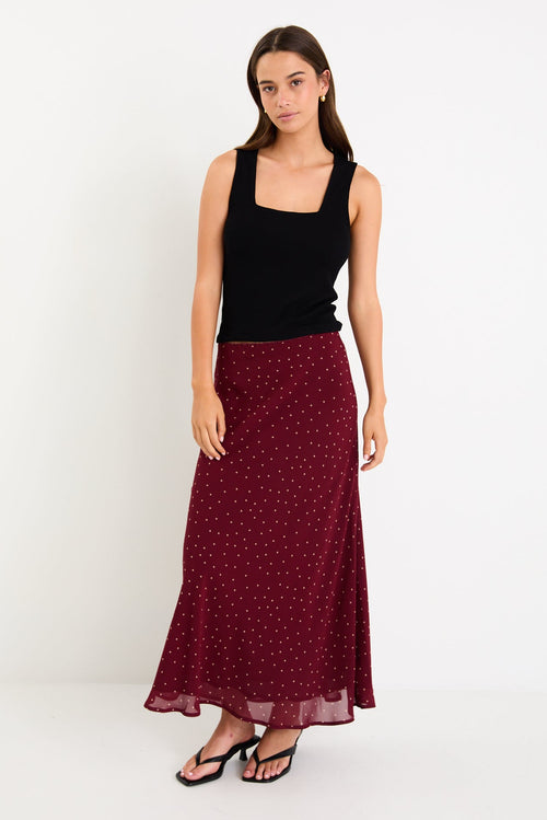 Model wearing a burgundy polka dot satin midi skirt with a bias-cut silhouette and a soft drape