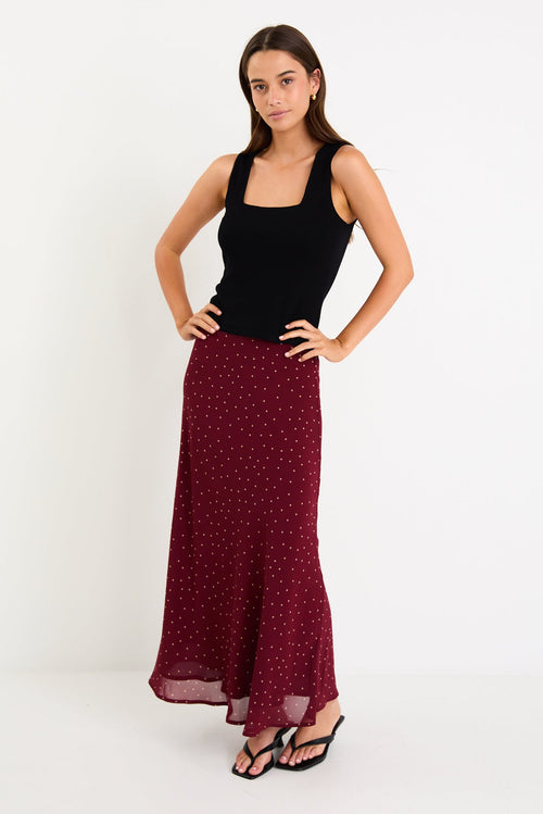 Model wearing a burgundy polka dot satin midi skirt with a bias-cut silhouette and a soft drape