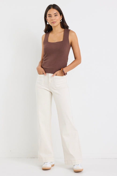 model wears a brown tank top with cream jeans
