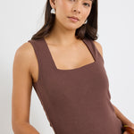 model wears a brown tank top with cream jeans