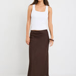 Woman wearing a white tank top and brown skirt on a white background