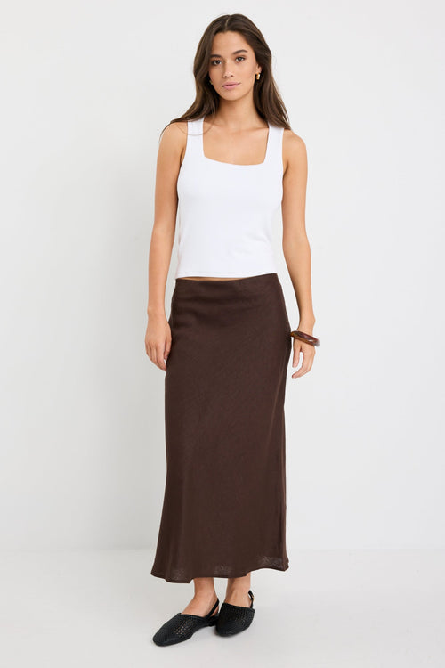 model wearing a white tank and brown skirt
