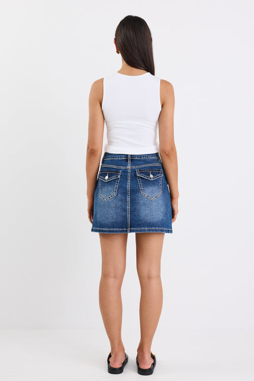A mid-blue mini skirt with front pockets, made from a stretchy cotton blend. Features a classic denim wash, with 99% cotton and 1% elastane for a comfortable, breathable fit.
