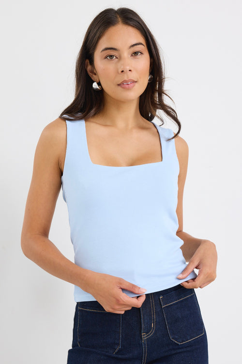 woman wearing a pale blue square-neck sleeveless tank paired with indigo jeans