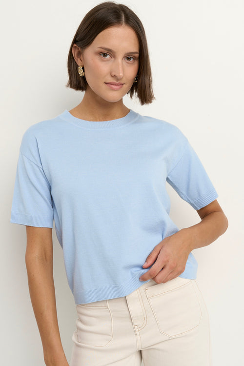 model wears a light blue knit t-shirt with ecru wide leg jeans