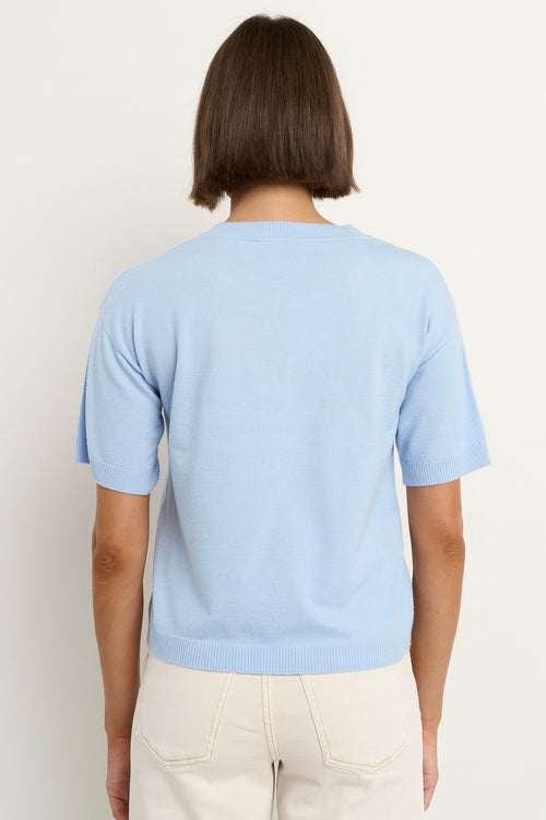 model wears a light blue knit t-shirt with ecru wide leg jeans