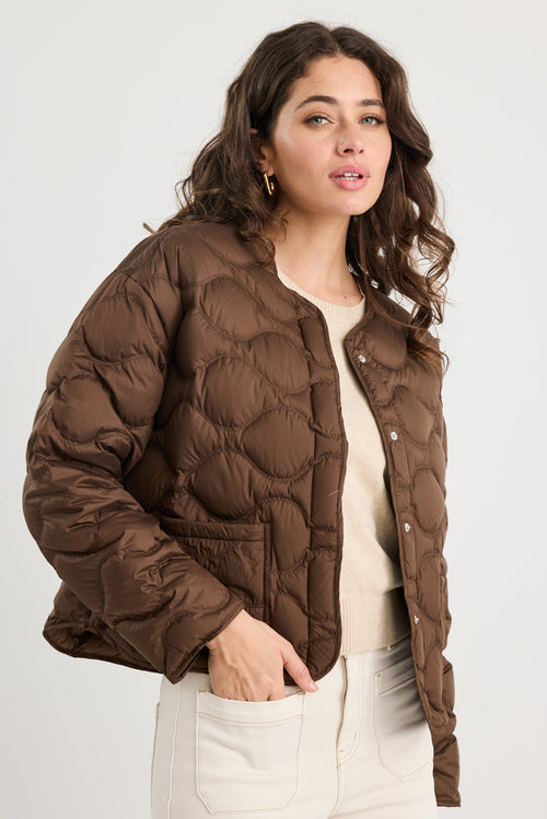 Woman wearing a brown puffer jacket on a white background