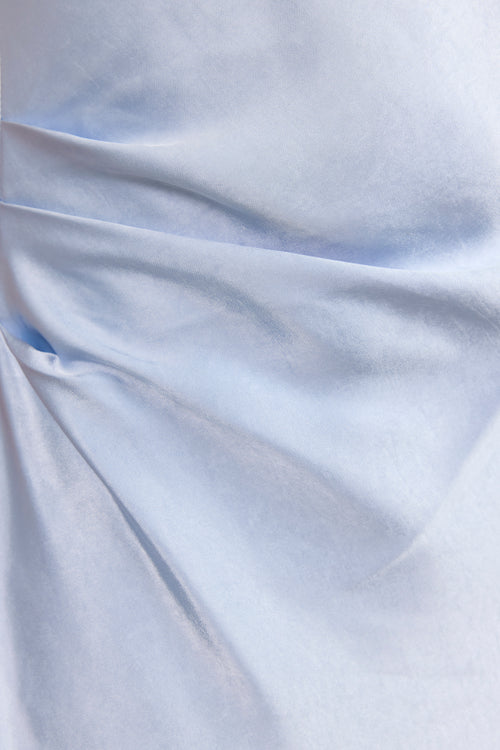 A close-up of draped light blue fabric with soft folds and a smooth texture.