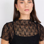 Woman wearing a black lace top against a white background