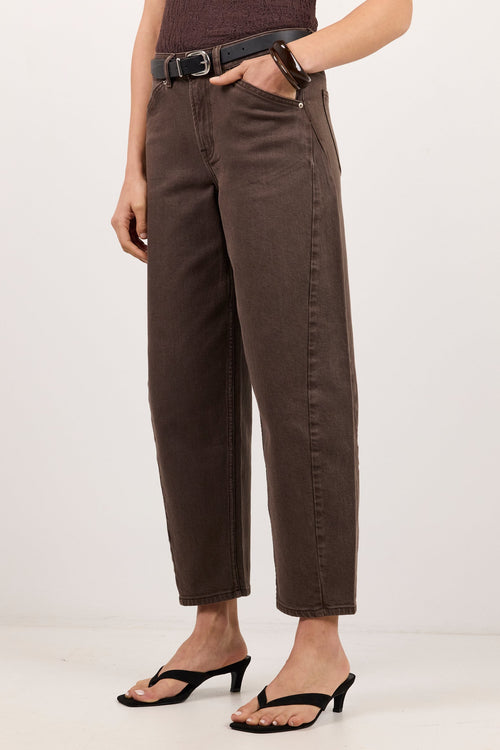 A model wearing dark brown cropped pants with a black belt, paired with a dark brown textured top and black heeled thong sandals, standing against a plain white studio background.