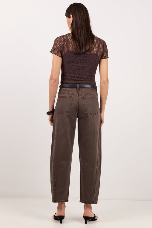 A woman is shown from the back wearing a dark brown lace short-sleeve top, brown wide-leg cropped pants, a black belt, and black heels, set against a plain white studio background.