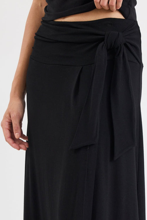 Person wearing a black wrap skirt on a white background