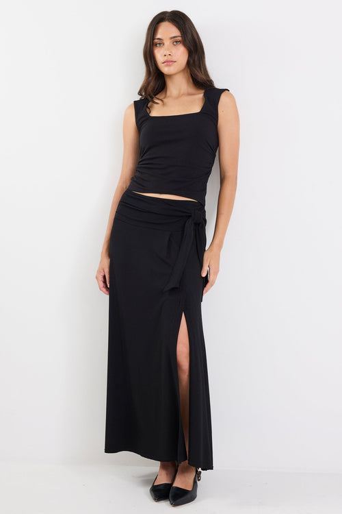 Woman wearing a black sleeveless top and long skirt on a white background