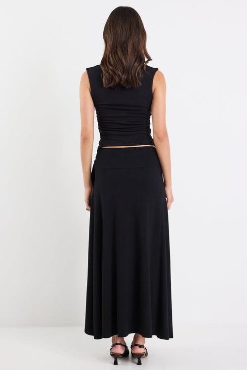 Woman wearing a black sleeveless top and long skirt on a white background