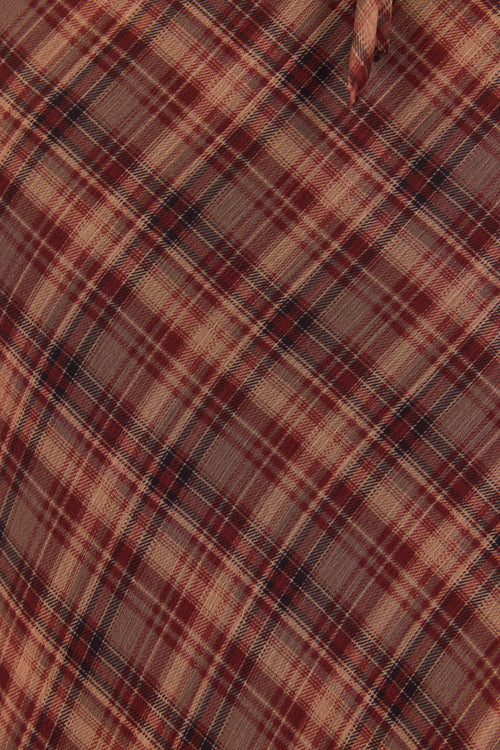Close-up of a plaid fabric with brown, beige, and black colors.