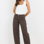Woman wearing a white tank top and brown pants on a white background