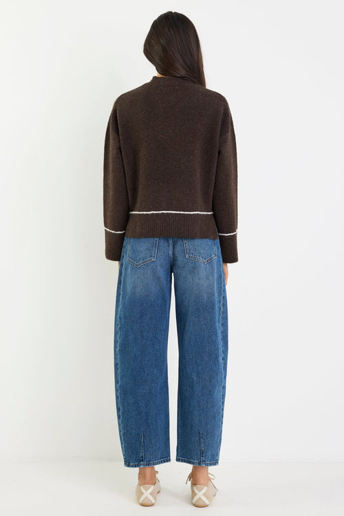 Person wearing a brown sweater and blue jeans on a white background