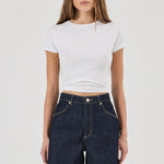 Woman wearing a white crop top and dark denim skirt on a white background