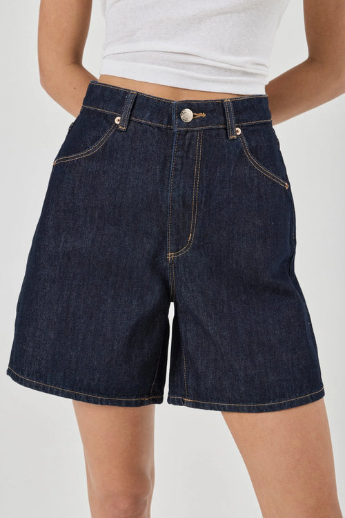 Person wearing dark blue denim shorts on a white background