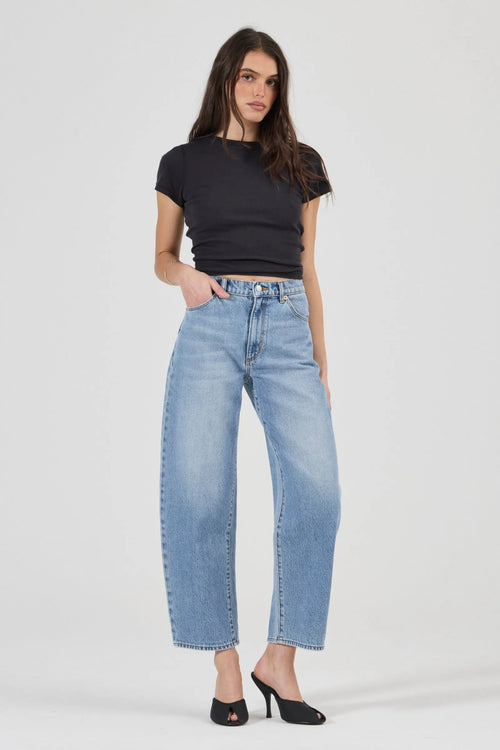 Woman wearing blue jeans and a black top on a white background