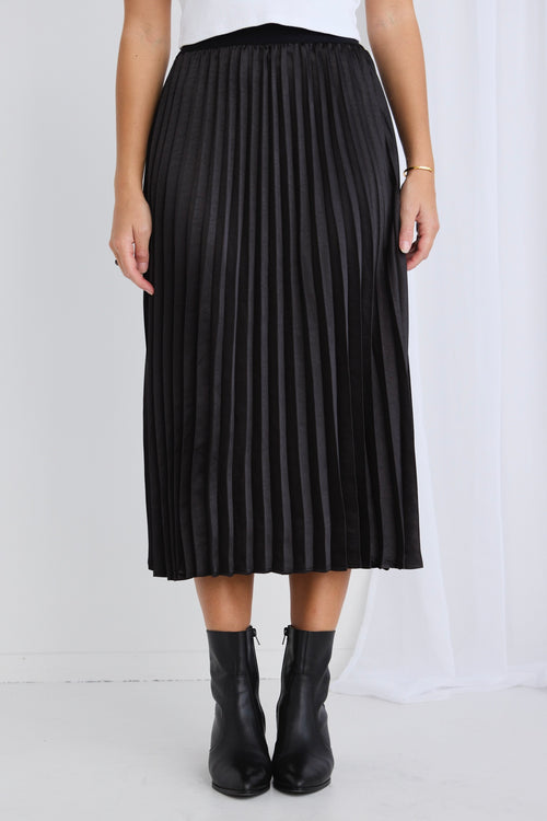 model wears a black pleated midi skirt
