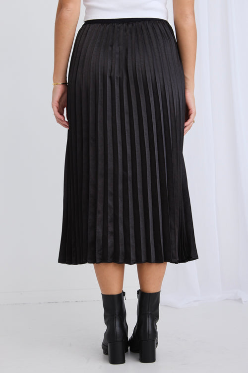 model wears a black pleated midi skirt