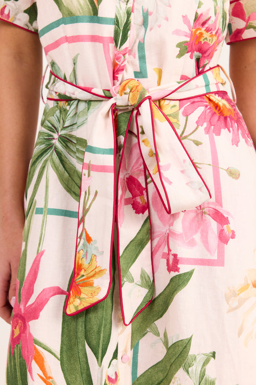 Close-up of a floral wrap dress with a matching self-tie belt, featuring pink flowers, green leaves, and a pink geometric pattern on a white background.
