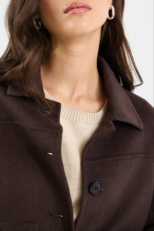 Woman wearing a brown coat with a plain background