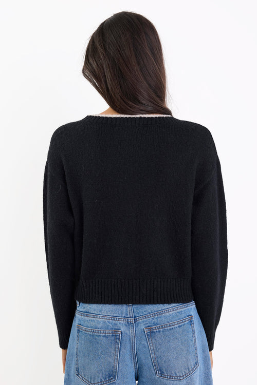 Person wearing a black sweater and blue jeans on a white background