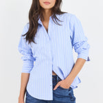 Woman wearing a light blue striped shirt and jeans on a white background