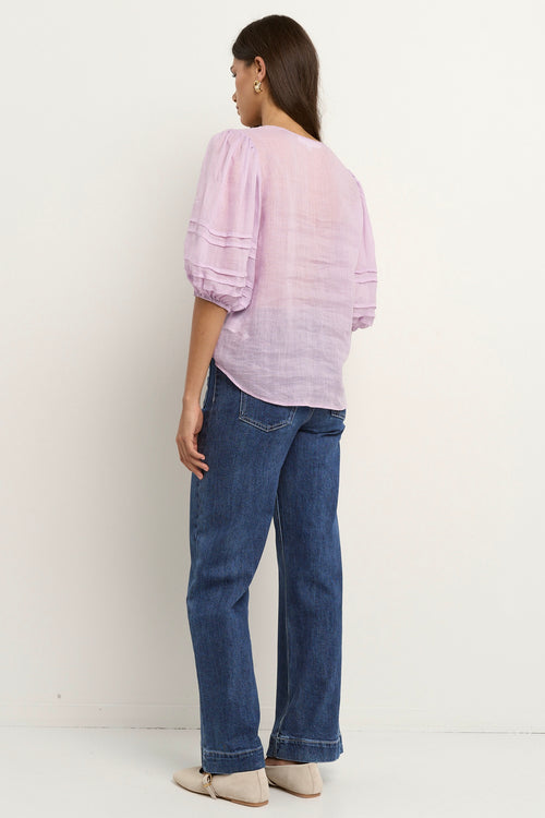 model wears a purple linen blouse with dark blue jeans
