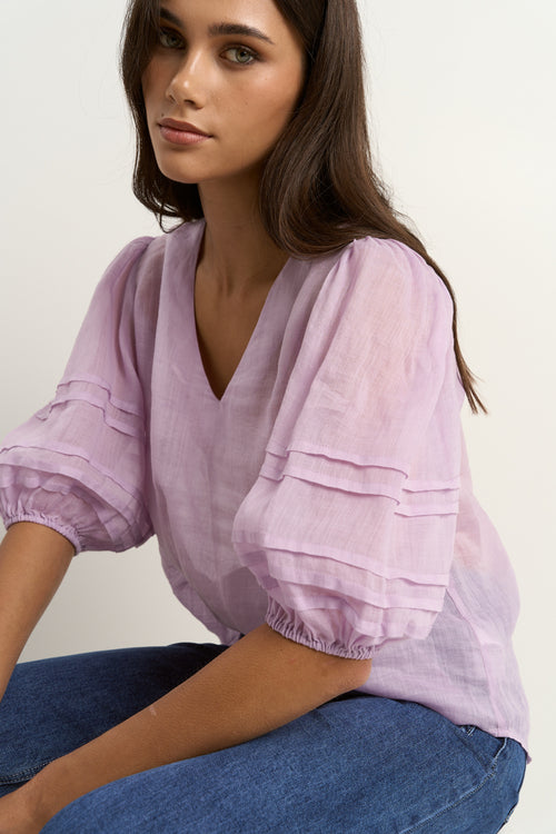 model wears a purple linen blouse with dark blue jeans