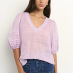 model wears a purple linen blouse with dark blue jeans