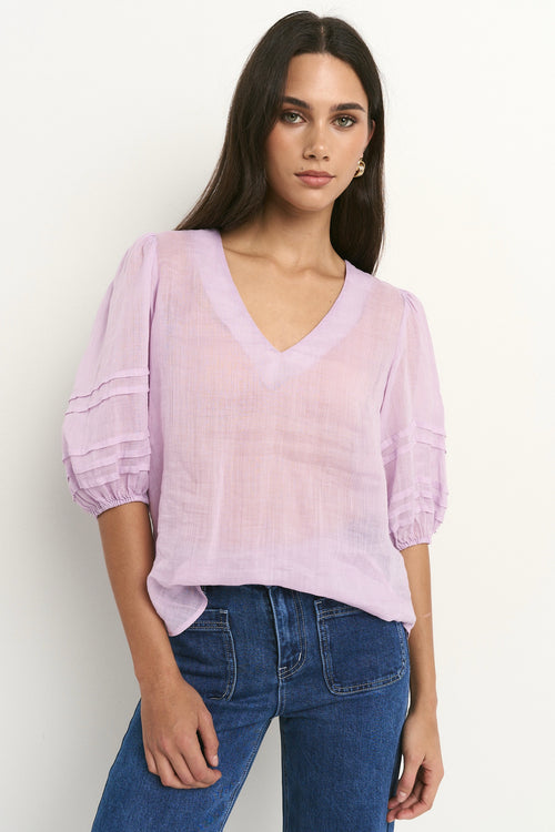model wears a purple linen blouse with dark blue jeans