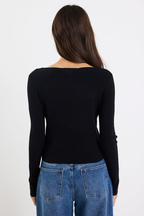 Person wearing a black long-sleeve top and blue jeans on a white background