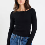 Woman wearing a black long-sleeve top and blue jeans on a white background